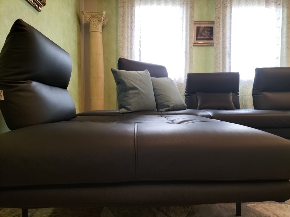 Divano in pelle con schienali traslanti, poggiatesta regolabili manualmente e bracciolo estensibile