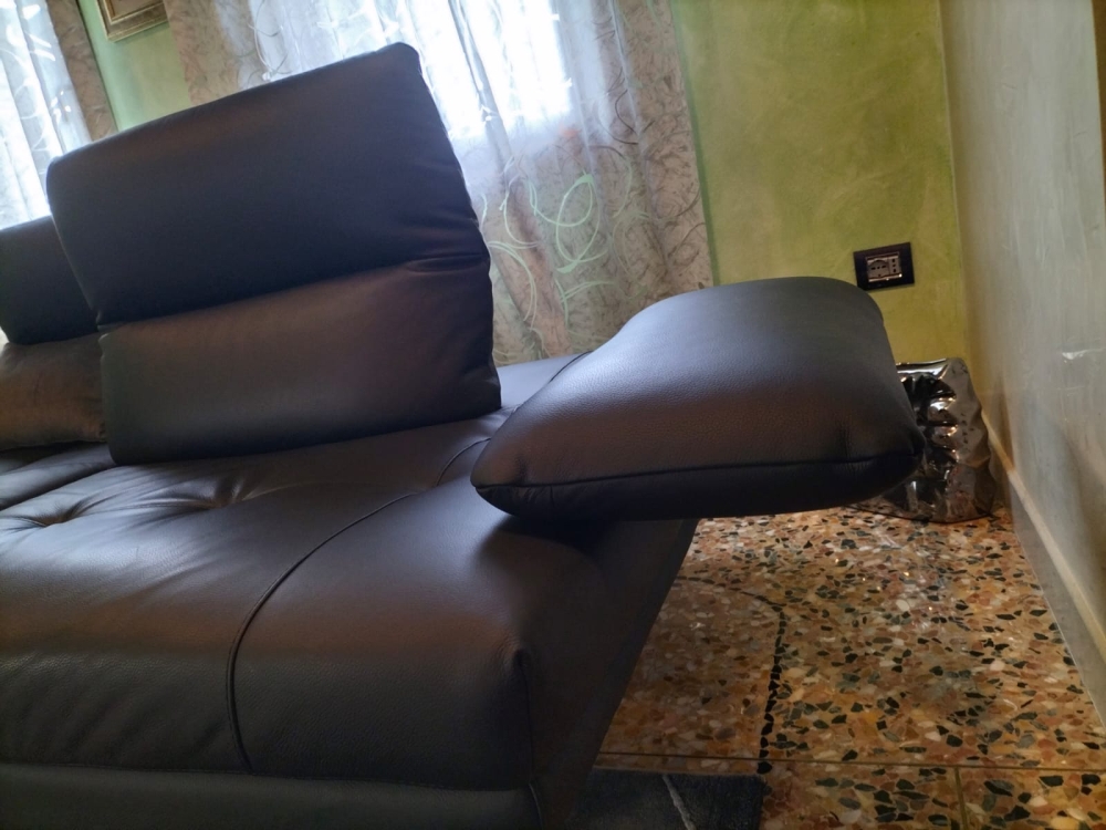 Divano in pelle con schienali traslanti, poggiatesta regolabili manualmente e bracciolo estensibile